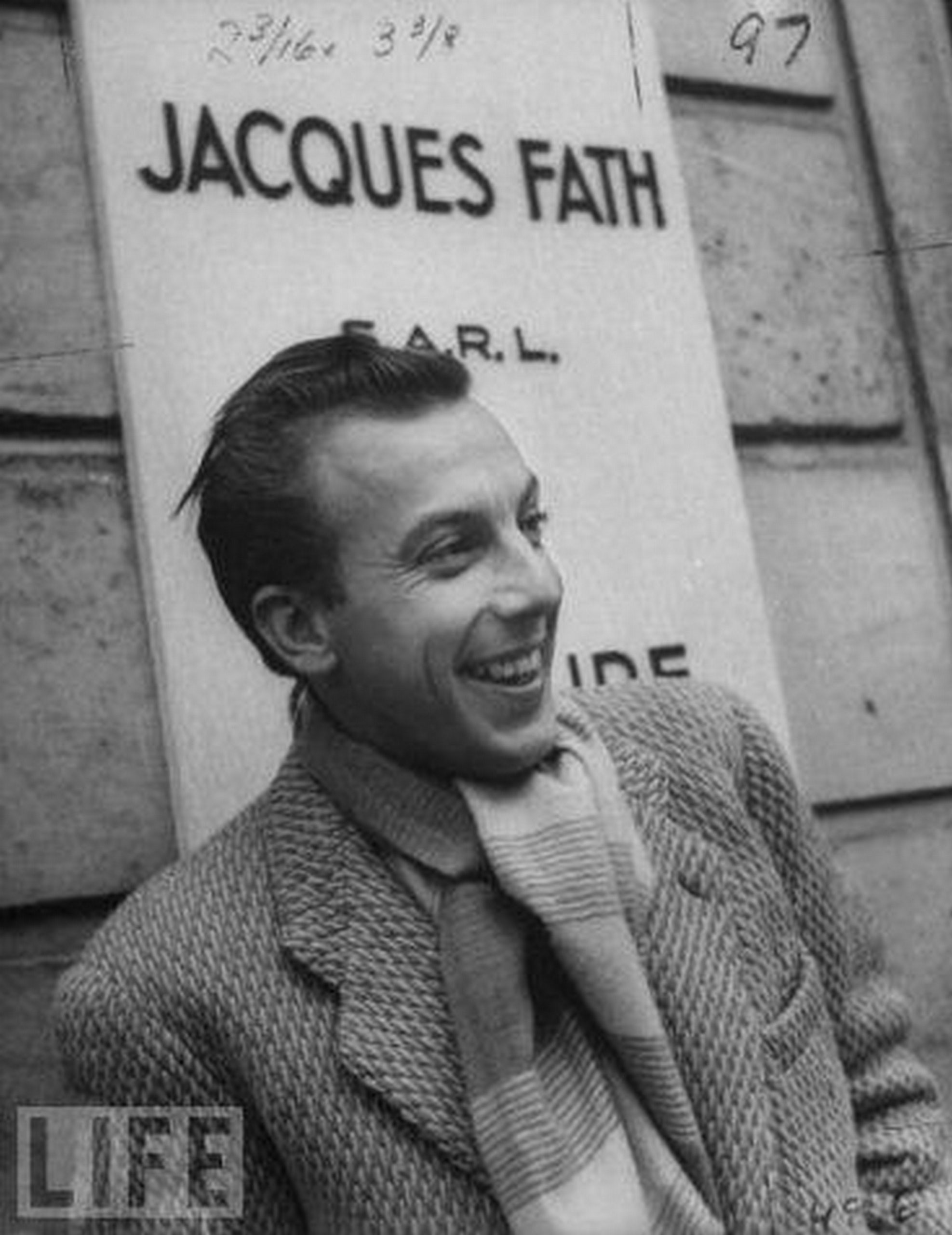 Jacques Fath devant l’entrée de sa maison de couture, avenue Pierre 1er de Serbie, Paris 8e (Life, 1952). Rival de Dior et Balmain, autodidacte revendiqué, Fath développa sa maison de couture pendant l’Occupation, faisant d’elle une entreprise prospère (voir aussi pastille 11). Son style audacieux, joyeux et emblématique du « chic parisien » le rendit célèbre après-guerre, jusqu’à sa mort prématurée d’une leucémie à l’âge de 43 ans, en 1954.<br><br>